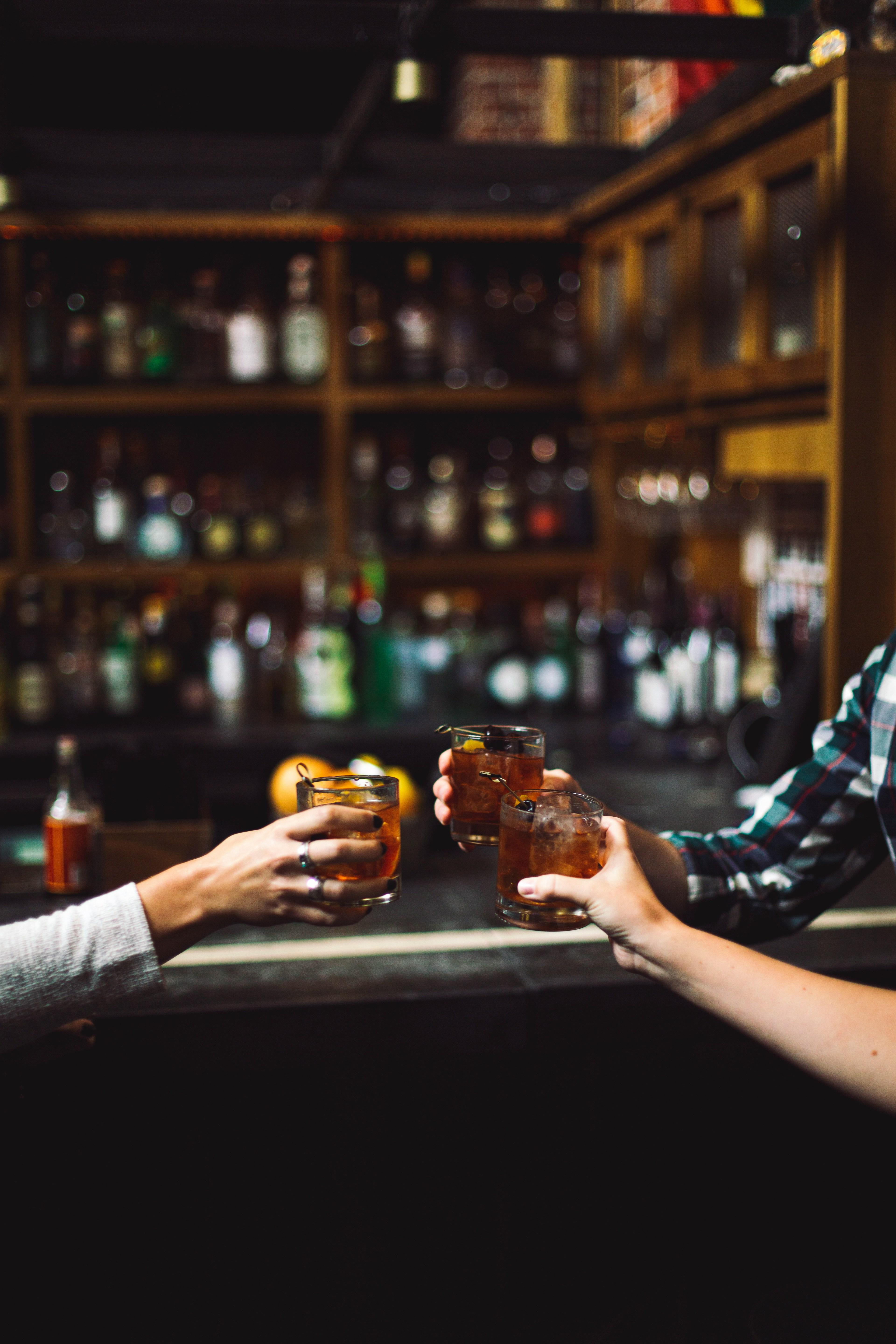 Dos personas brindando en la barra de un bar