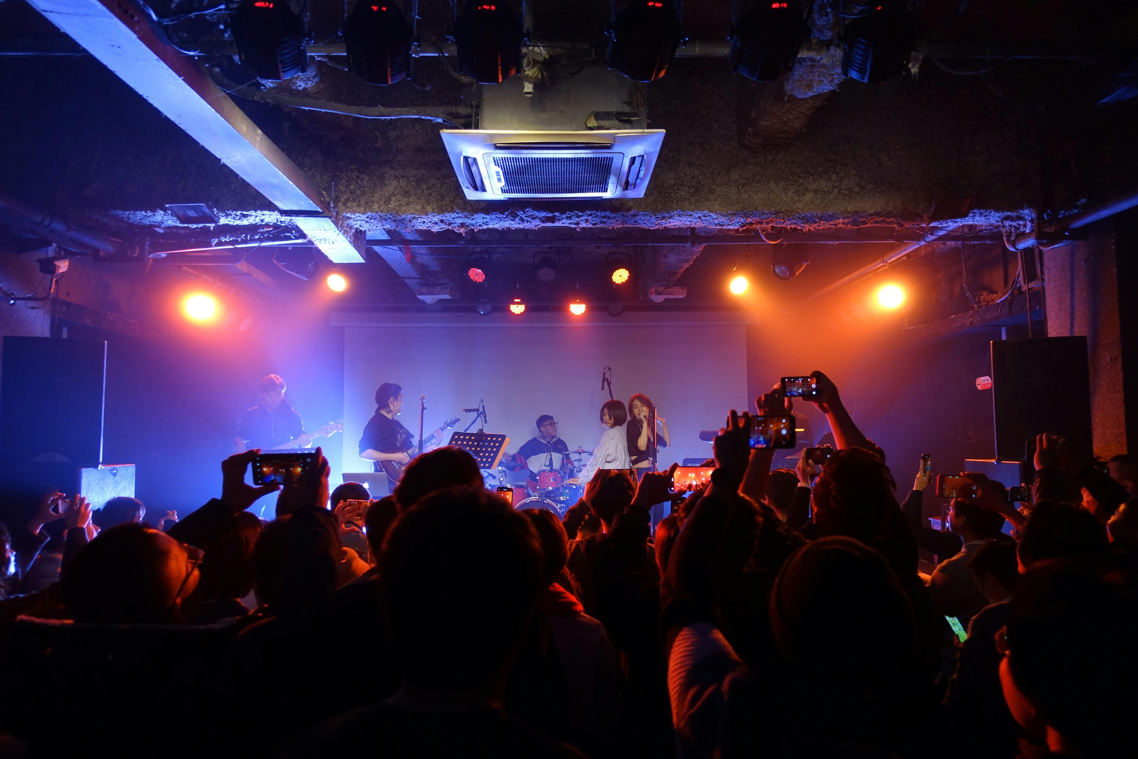 Un grupo tocando en directo en una sala pequeña llena de gente