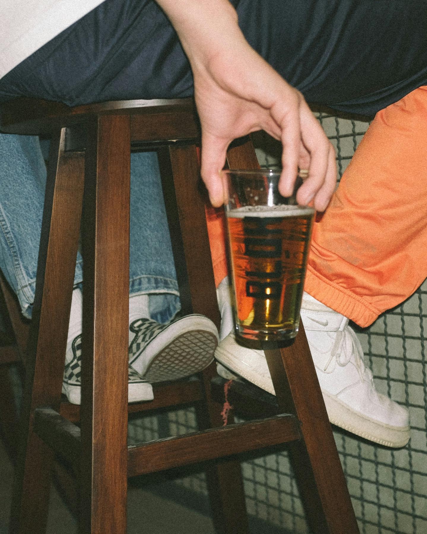 Una caña de cerveza en la mano de un cliente sentado en un taburete de bar