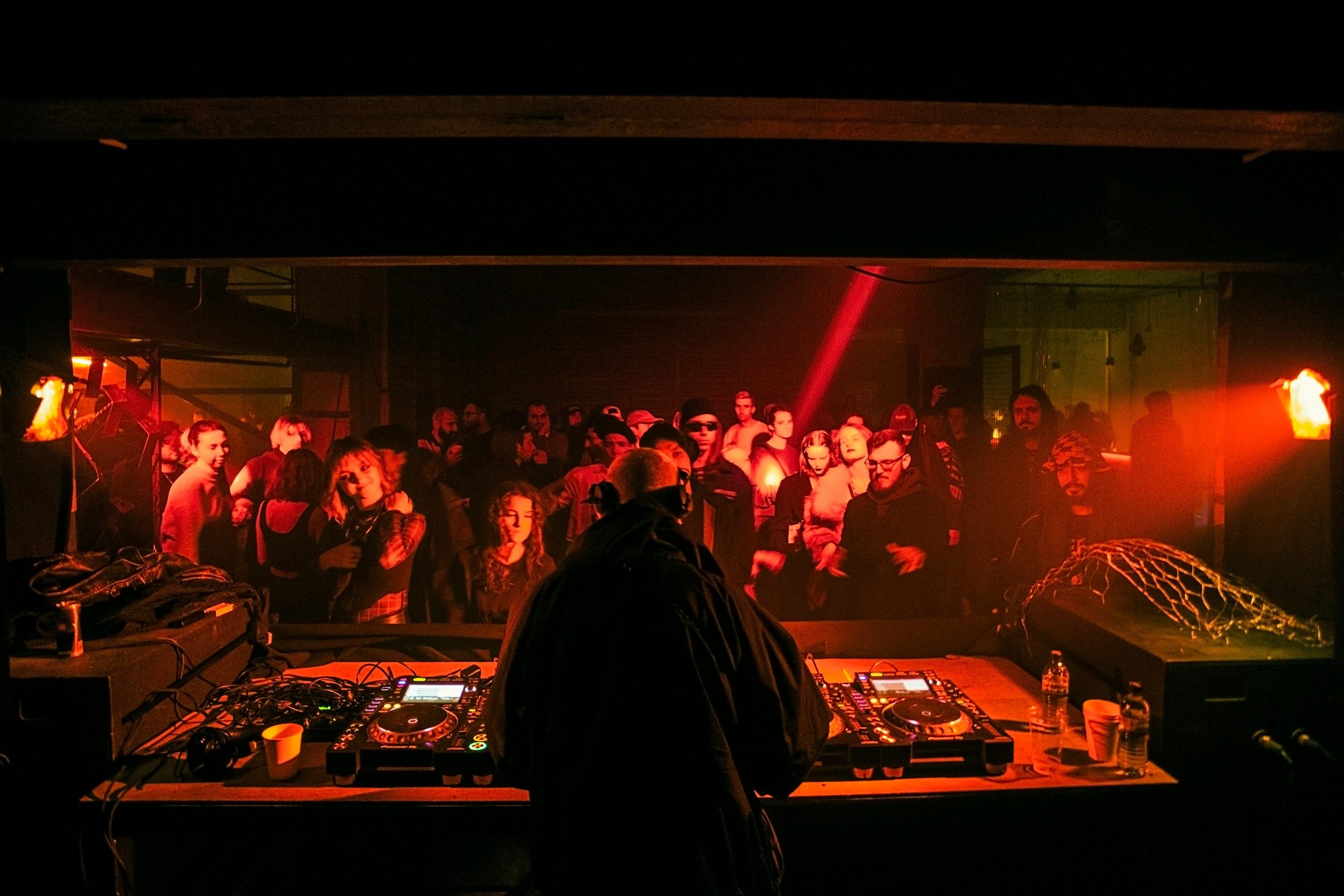 Un DJ pinchando en la cabina de un bar lleno de gente