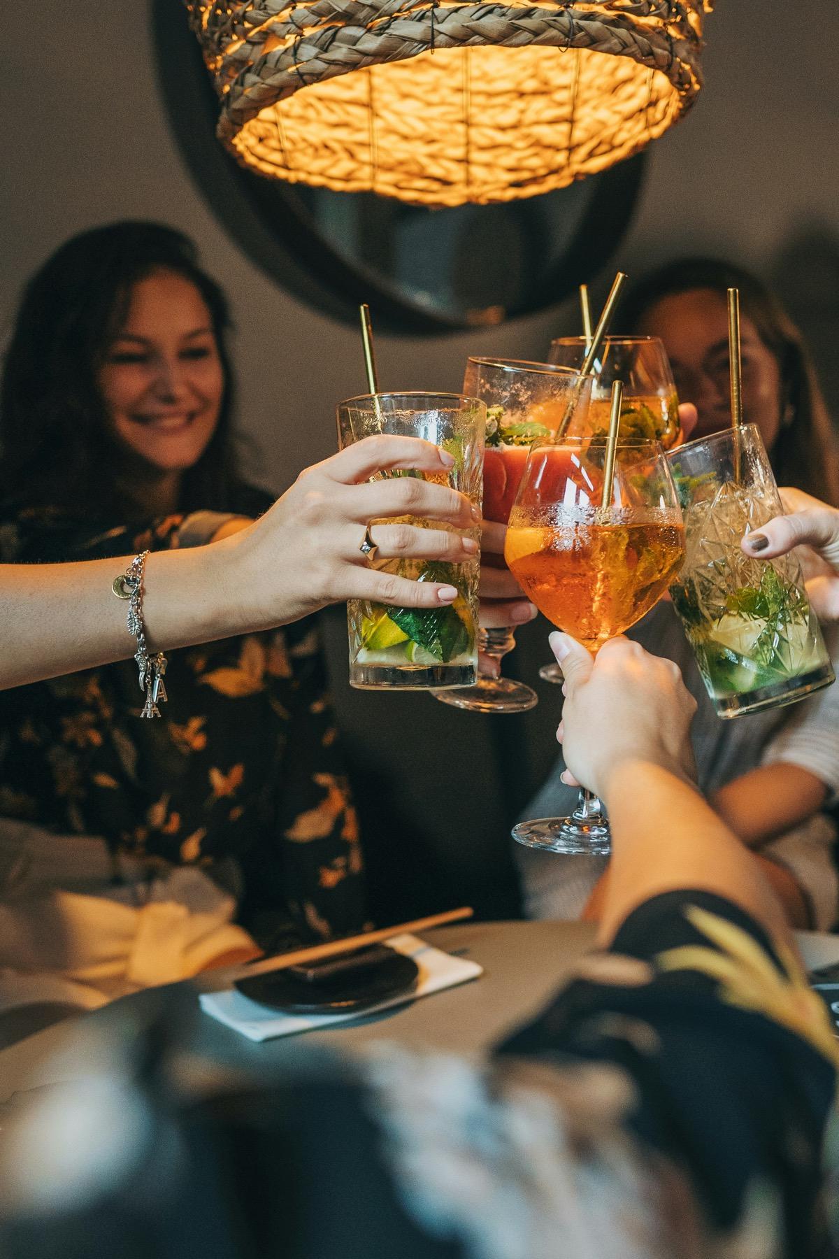 Un grupo de amigas brindando con cócteles en la mesa de un bar